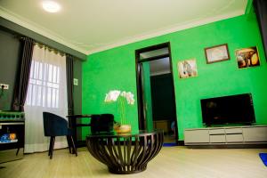 een woonkamer met groene muren en een tv bij Blaize Affaire apartments in Kampala