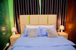 a bedroom with a bed with blue and white pillows at Blaize Affaire apartments in Kampala