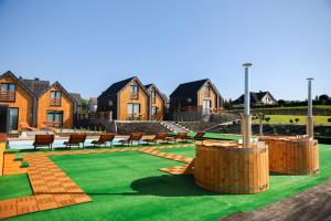 a yard with chairs and grass and houses at Zielona Osada Apartamenty in Ciężkowice
