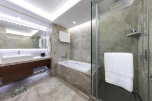 a bathroom with a shower and a sink and a tub at New World Millennium Hong Kong Hotel in Hong Kong