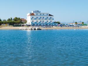 duży biały budynek siedzący na plaży obok wody w obiekcie Hotel Strand w mieście Marina di Montenero