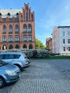 dos coches estacionados frente a un edificio de ladrillo en Belle époque appartement I The Artdrake Collection by LUX RELAX Apartamenty Kołobrzeg, en Koszalin