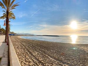 a sandy beach with palm trees and the ocean at La CASA BLAVA in Cubelles