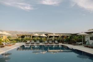 ein Pool in einem Resort mit Liegestühlen und Sonnenschirmen in der Unterkunft Sails on Kos Ecolux Tented Village in Marmari