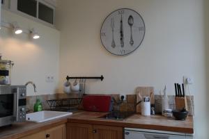 una cocina con un reloj colgando en la pared en Penthouse Apartment overlooking Place Carnot, en Carcassonne