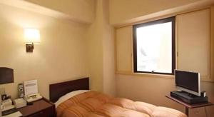 上田市Ueda Plaza Hotel的一间卧室配有一张床、一张书桌和一个窗户。