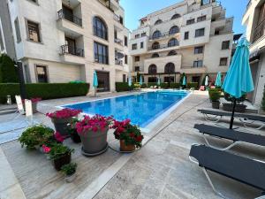 a swimming pool with potted plants next to a building at Apartments Amara Sunny Beach in Sunny Beach