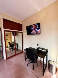 a room with a desk and a television on the wall at Departamento Fila in Puerto Escondido