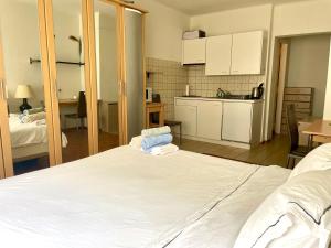 a room with a white bed and a kitchen at 300m from the train station in Lausanne