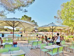 a group of people sitting at tables and umbrellas at Carazur Mobilhomes Camping Fréjus in Fréjus