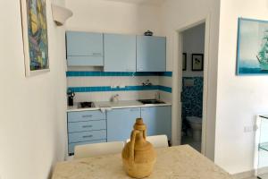 a kitchen with blue cabinets and a table with a vase on it at FA Appartamenti Rurali in Galatone +3 photos