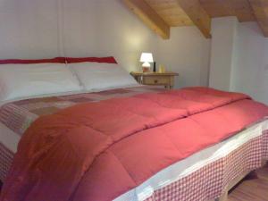 ボルゴにあるChalet La Montagnolaのベッドルーム1室(ベッドに大きな赤い掛け布団付)
