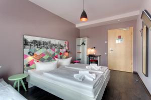 Un dormitorio con dos camas y una pared colorida. en MEININGER Hotel Berlin Alexanderplatz, en Berlín
