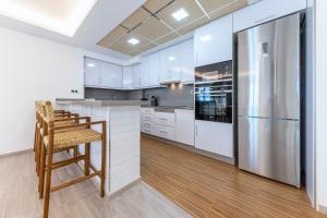 a kitchen with white cabinets and a stainless steel refrigerator at Montiboli Apartments by Buccara in Villajoyosa