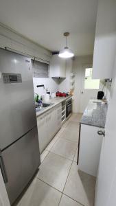 a kitchen with white cabinets and a stainless steel refrigerator at Comfortable y central depto 2D 2B with parking in Los Ángeles