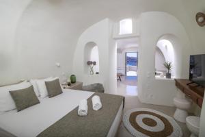 a white bedroom with a large bed and a living room at Kyrkos Collection in Fira