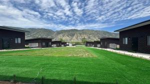a large green yard with mountains in the background at Kolsay Lakes in Saty