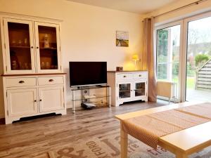 a living room with a television and white cabinets at Ferienwohnung Stadtfelder in Böhl
