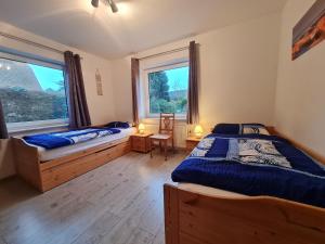 a bedroom with two beds and two windows at Ferienwohnung Stadtfelder in Böhl
