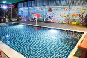 een groot zwembad met een muurschildering op de muur bij รีสอร์ทบ้านพระร่วง 