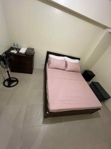 un lit avec des draps roses dans une chambre avec un bureau dans l'établissement Q Inn Serin East Tagaytay City, à Calo