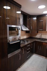 a kitchen with wooden cabinets and a stove top oven at Luxury 1BR Near the Airport in Cairo