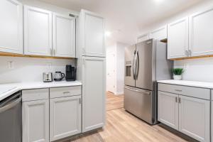 Una cocina con gabinetes blancos y un refrigerador de acero inoxidable. en Modern Basement Suite, 2BR Sofa Bed, Parking, en Greensboro