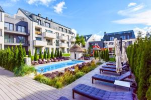 un hôtel avec une piscine, des chaises et un bâtiment dans l'établissement Summer, à Palanga