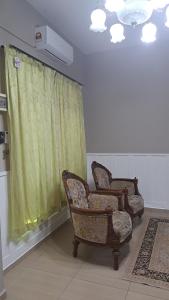 two chairs in a room with a green curtain at A&W RnR in Kampong Baharu Sungai Udang +2 photos