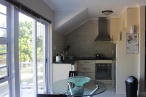 a kitchen with a glass table and a refrigerator at Milas Place in Somerset West