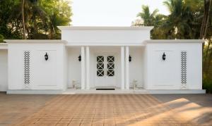 a white house with a white door and palm trees at Villa Raag in Agonda