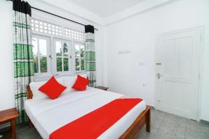 a bedroom with a large white bed with red pillows at Tropical Breeze Negombo in Negombo