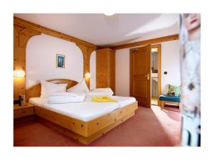 a bedroom with a wooden bed with white sheets at Alpenhotel Linserhof in Imst