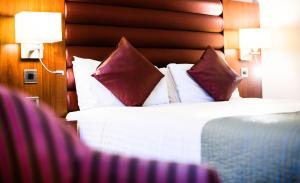 Habitación de hotel con cama con almohadas rojas y blancas en Drayton Manor Hotel, en Tamworth