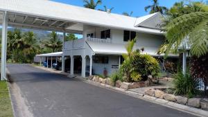 a white building with palm trees and a street at Tully Motel in Tully
