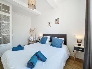ein Schlafzimmer mit einem großen weißen Bett mit blauen Kissen in der Unterkunft L'Alcazar - Appartement à deux pas des halles - Climatisation in Narbonne