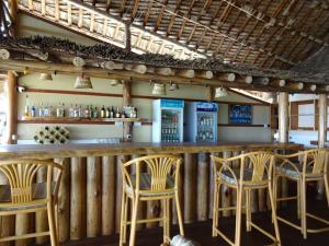 a bar with wooden chairs and a counter with drinks at Barry's Beach Resort Pangani in Mkwaja