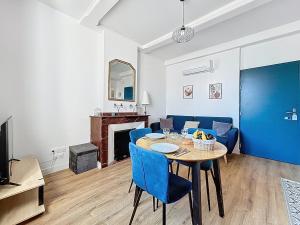 ein Wohnzimmer mit einem Tisch und blauen Stühlen in der Unterkunft L'Alcazar - Appartement à deux pas des halles - Climatisation in Narbonne + 2 Fotos