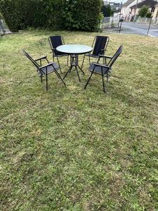 three chairs and a table in the grass at La maison des amis in Beauvais