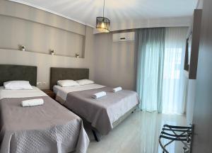 a hotel room with two beds and a window at Lia Rooms in Paralia Katerinis +25 photos