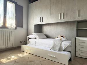 a bedroom with two beds with white cabinets at Elsa, giardino e relax in Zambra