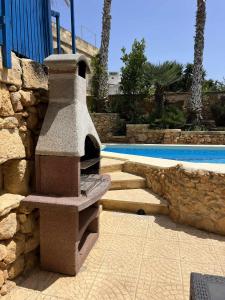 a stone fireplace sitting next to a swimming pool at Ta' Tereża Farmhouse in Xagħra