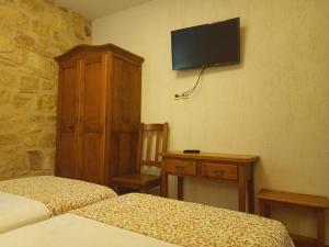 ein Schlafzimmer mit zwei Betten und einem Fernseher an der Wand in der Unterkunft hostal Decerca Prádena in Prádena