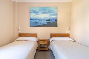 Dos camas en una habitación con un cuadro en la pared. en Ponent Cala Ratjada Apartments A, en Cala Ratjada