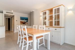 Una cocina con una mesa de madera y gabinetes blancos. en Ponent Cala Ratjada Apartments A, en Cala Ratjada