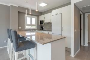 cocina con armarios blancos y barra con taburetes en Ponent Cala Ratjada Apartments A, en Cala Ratjada
