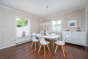 a dining room with a white table and chairs at Ferienhaus Witt in Neue Tiefe Fehmarn +21 photos