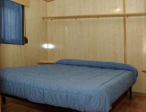 a bedroom with a bed with a blue bedspread at Bungalows Granja Escuela Arlanzón in Arlanzón