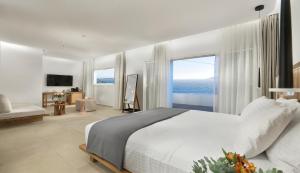 a bedroom with a large bed and a large window at Etere Luxury Suites in Agios Ioannis Mykonos