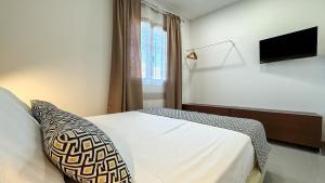 a bedroom with a bed with a pillow and a television at Tevergad Suites & Rooms in Terrasini